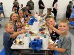 children smiling while eating at a table