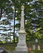 a tall, 1800s style gravestone, in the shape of an obelisk with an eagle perched on a ball on the top