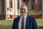 a man in a suit in tie in front of the Woodstock Academy building
