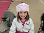 a child wearing a hat shaped like a pink cupcake with white frosting