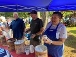 three people serving ice cream from large buckets