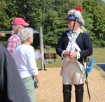 a man in a Revolutionary War-style uniform talks to people