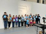 A group of people of all ages posing with paintings