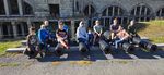 Scouts posing for a picture, sitting on cannons in front of fortifications