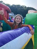 A child playing on a bounce house, holding a thumbs-up