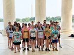 a group of students posing in a columned building, with the Washington Monument visible