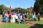 a group of people in modern and historic clothing pose with the tree
