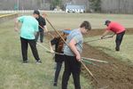 people raking dirt on a baseball field