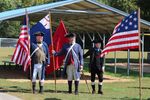 three men in Revolutionary War-style uniform pose with flags