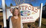A child posing with the school sign