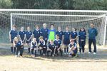 children in soccer uniforms posing in front of a goal