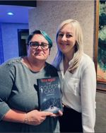 two women posing with a book