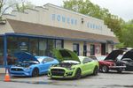several bright-colored sports cars in front of Bowen's garage, an old-fashioned style car dealership