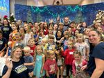 a large group of children posing in front of a Christmas-themed background