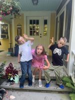 three children making silly faces on a doorstep