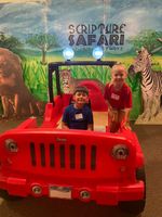 Children posing in front of a jeep in front of pictures of African wildlife