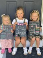 three children smiling holding posters that say it is the first day of school