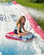 a child riding down a water slide in the sun, with foam everywhere