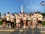 a group of students with the Washington Monument in the background, pictured in the evening