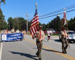 Scouts marching in a parade holding flags