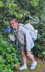 a girl smiling while smelling a blue flower