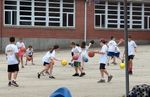 Children dribbling basketballs in a school parking lot