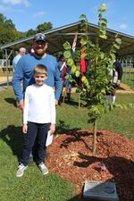 a man and a boy pose next to the tree