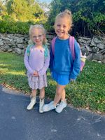 two girls posing in front of a stone wall