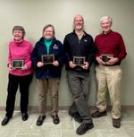 four people posing with awards