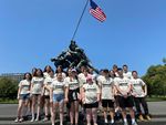 a group of students in front of a war memorial of soldiers raising a flag