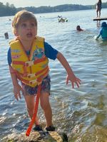 a child wearing a life jacket standing in a lake