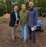 three men standing in a muddy clearing