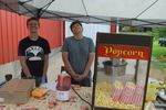two people posing with cider and a popcorn machine