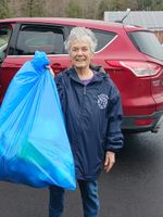 a woman posing with a filled, blue trash bag