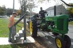 a man driving a tractor with a trailer full of people, and another man with a set of stairs to help them get off 