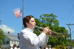 Isaac Torcellini playing a trumpet with a flag at half mast in the back