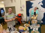 Two women posing in the school kitchen with baked goods
