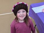 A child in a purple cupcake hat