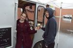 a woman standing in a delivery van hands an ice cream cone to a customer
