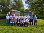 a group of people in uniforms in front of fire trucks