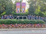 a group of students posing at a zoo entrance, with signs and bushes