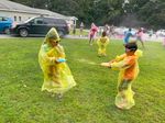 Two children playing in yellow ponchos outdoors