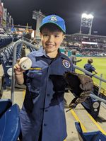a child posing with a baseball and glove at a baseball arena