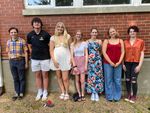 several college-aged people posing in front of a brick wall