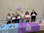 several people holding awards, with a table with cupcakes