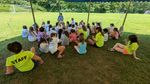 children sitting under a tent listening to an adult