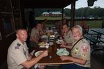 scouts and leaders in uniform eating at a table
